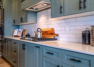 Cooking area of home with cabinets and exhaust hood over cooktop and countertop