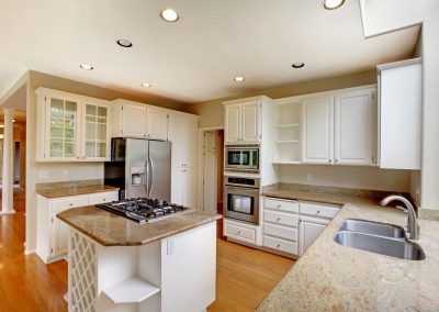 Classic American kitchen interior with white cabinets and built-in stainless steel fridge.
